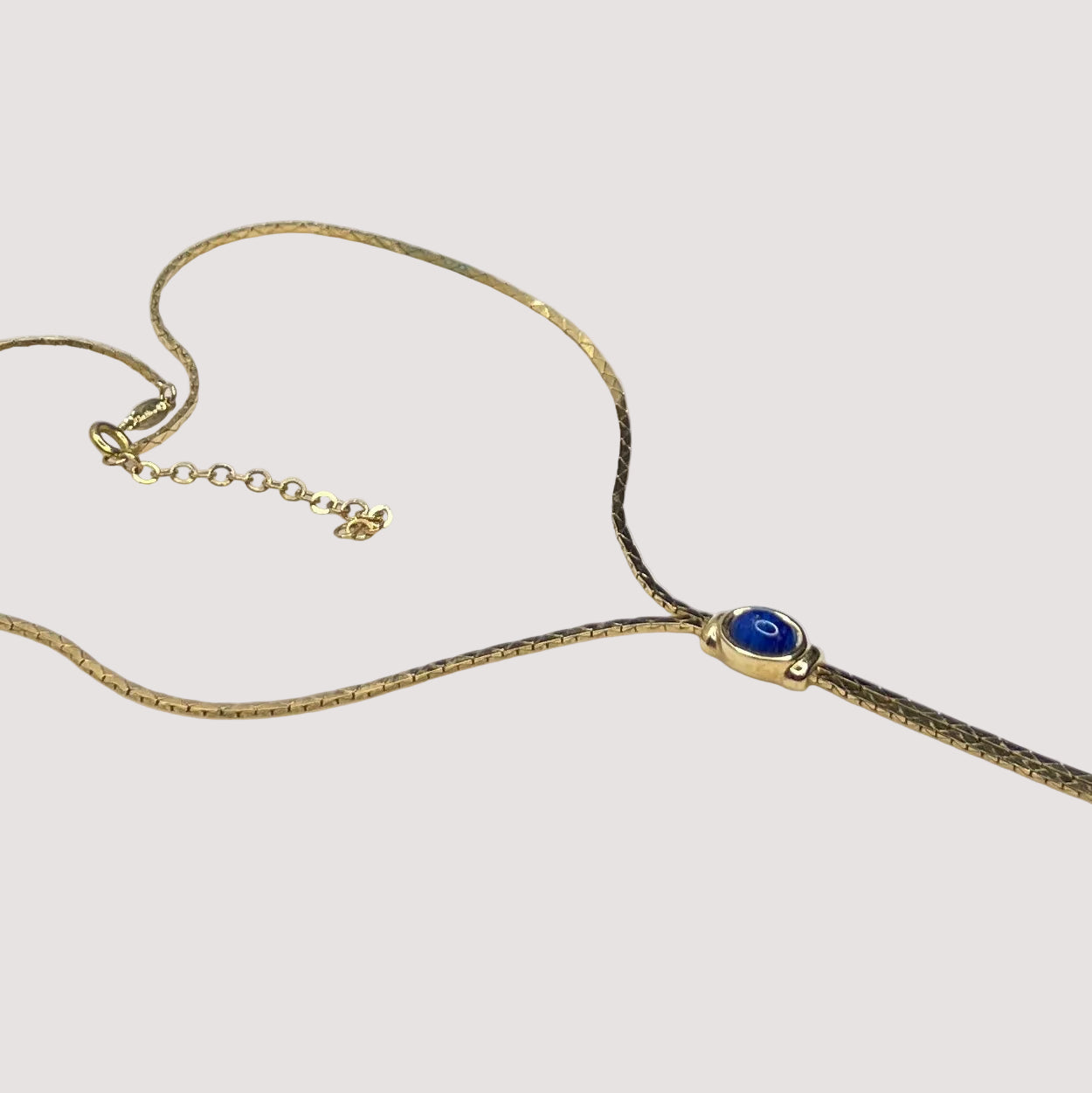 Full view of necklace with lariat drop and blue stone on white background