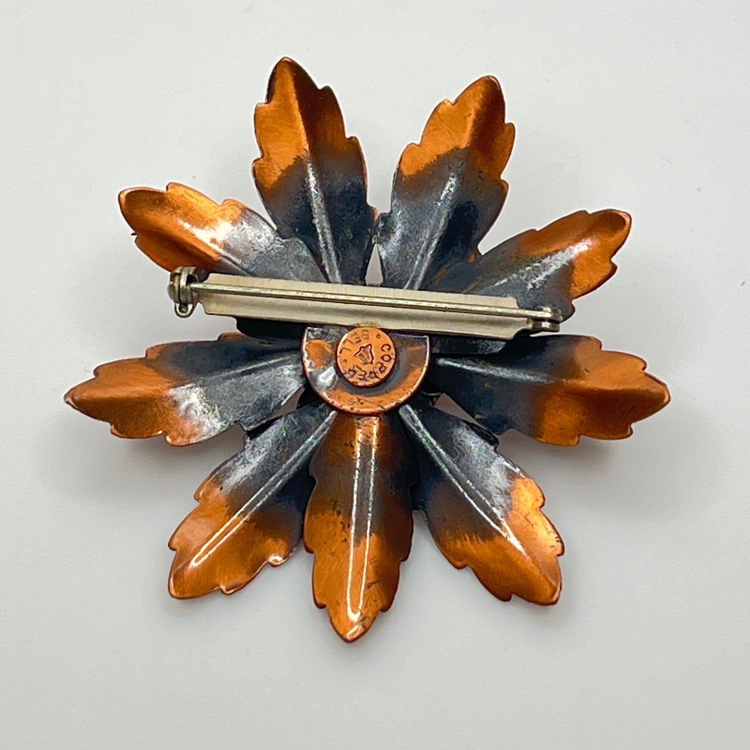 Reverse of copper brooch showing Copper Bell stamp and bell logo