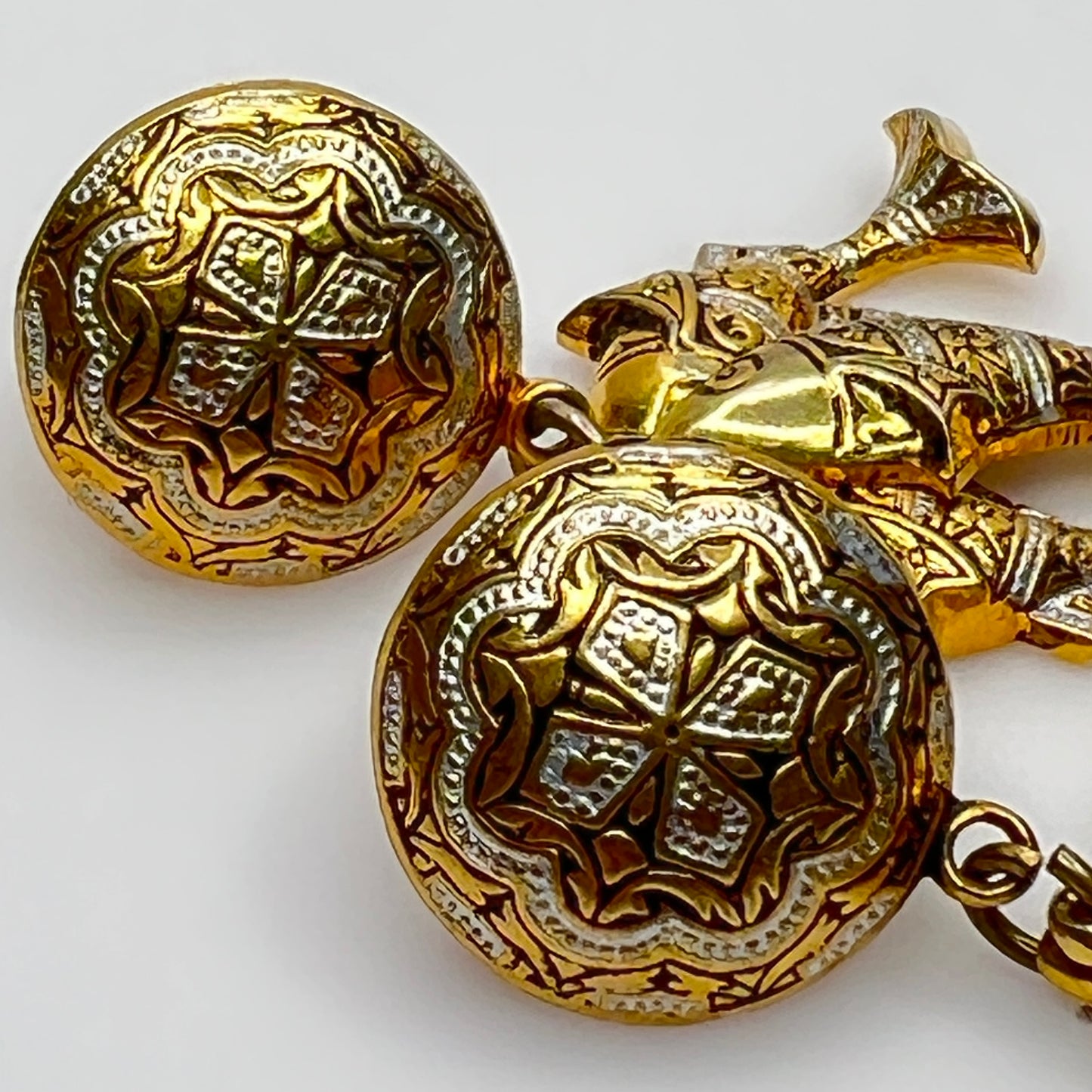 Close-up of ornate etched round tops in gold and silver damascene pattern