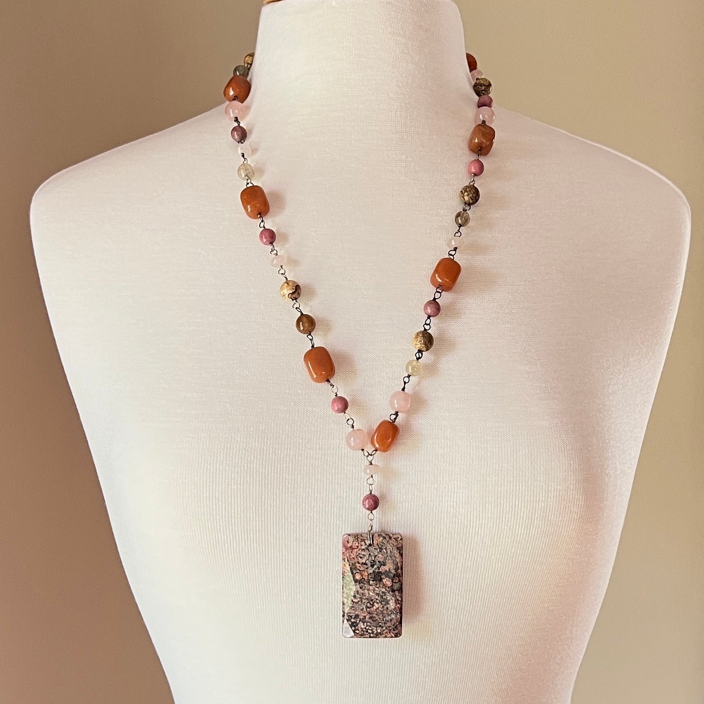 Long beaded gemstone necklace with granite pendant on mannequin bust