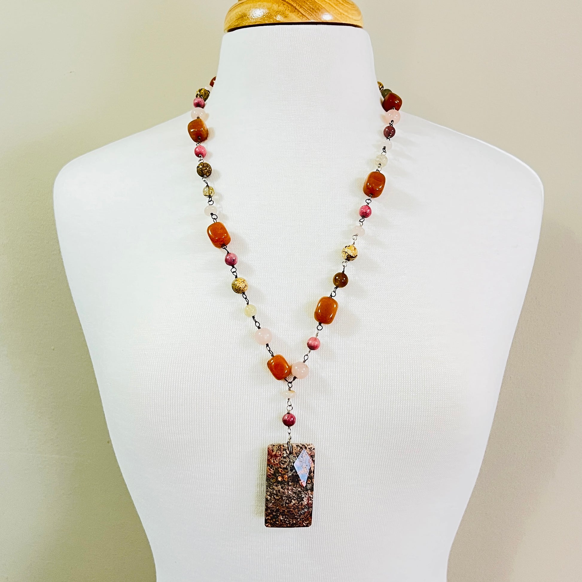 Long beaded gemstone necklace with granite pendant on mannequin bust