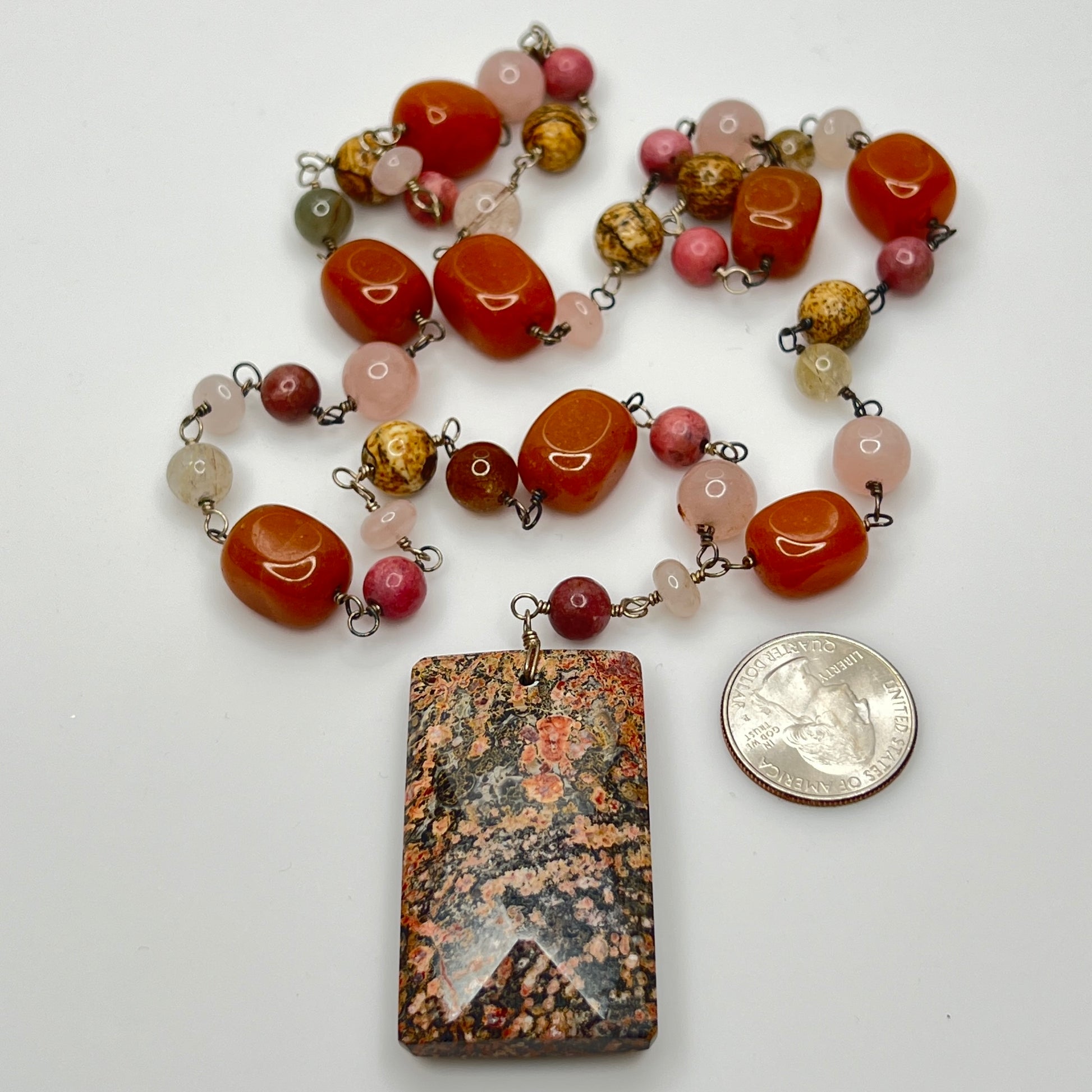 Full necklace with coin for scale, showing carnelian, quartz, and pink stone beads