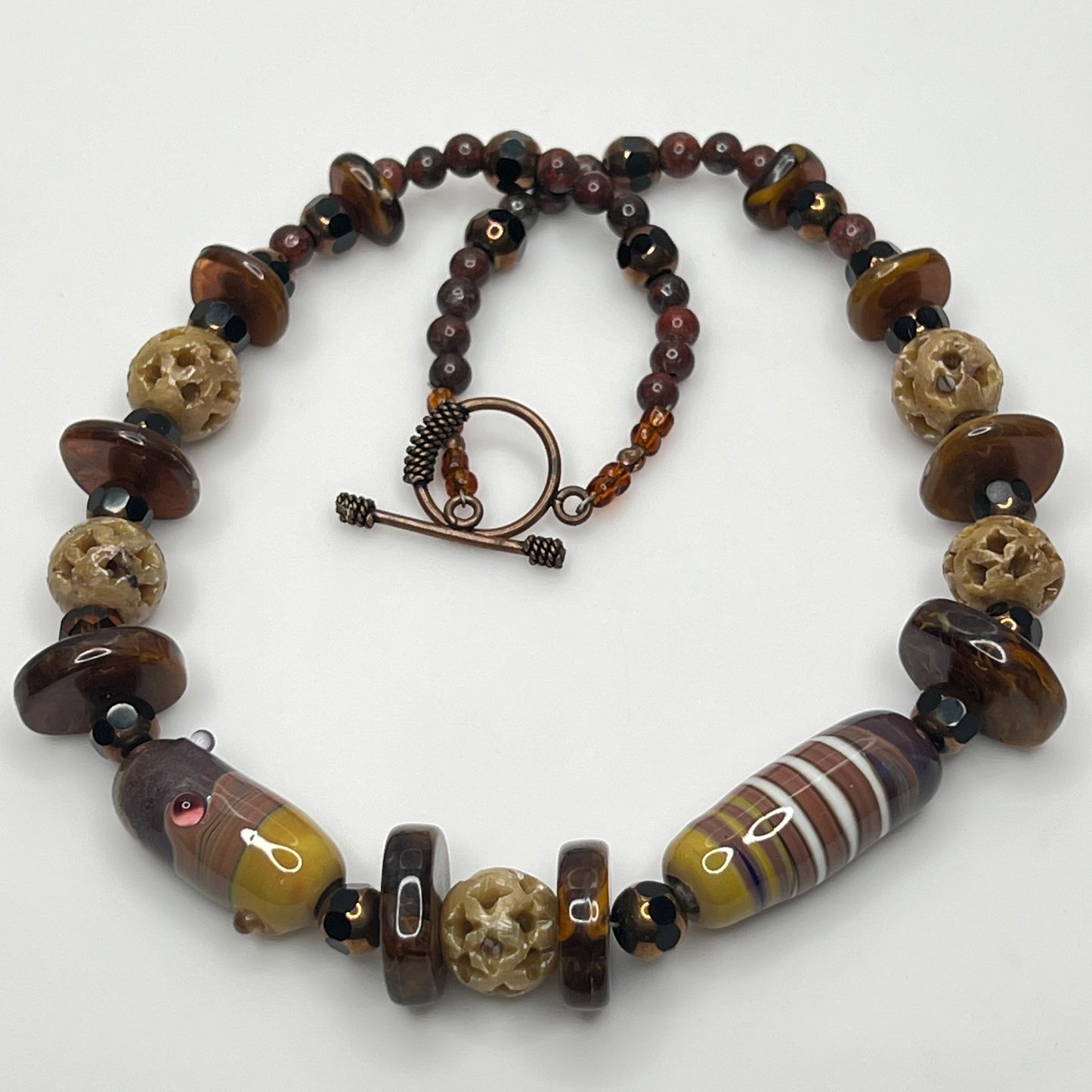 Vintage necklace with glass and carved stone beads in warm earthy tones