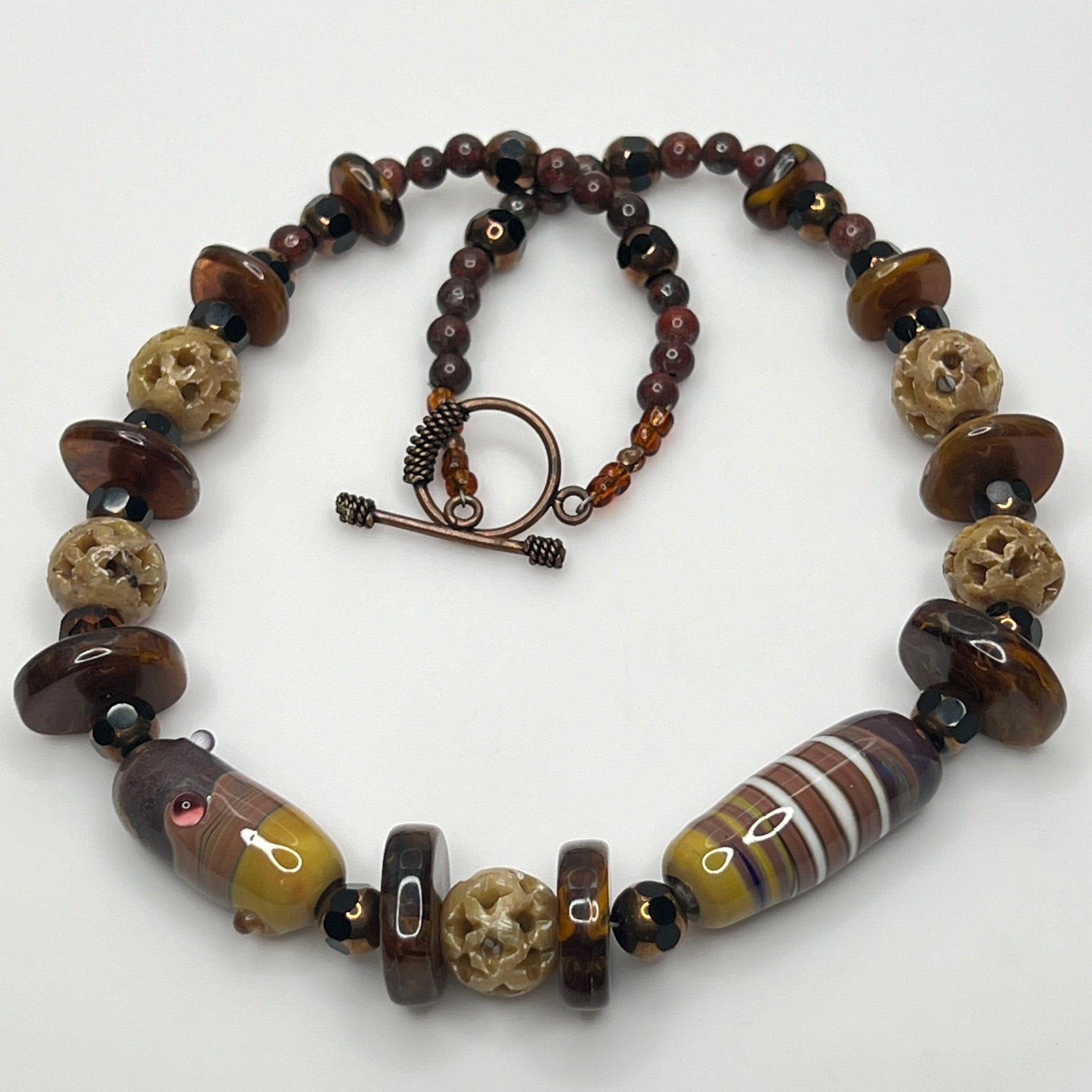 Vintage necklace with glass and carved stone beads in warm earthy tones