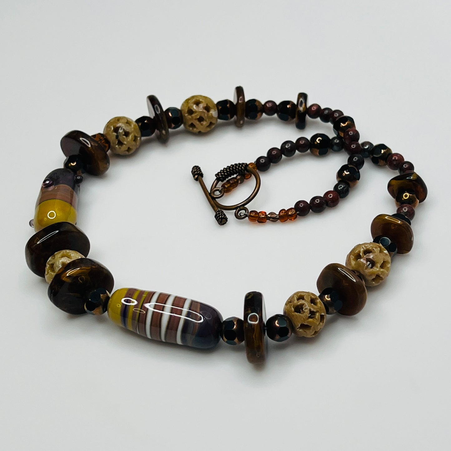 Vintage necklace with glass and carved stone beads in warm earthy tones