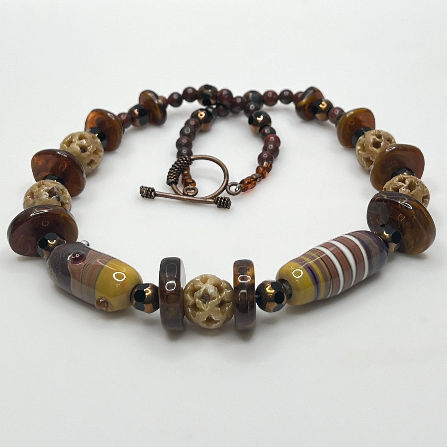 Vintage necklace with glass and carved stone beads in warm earthy tones