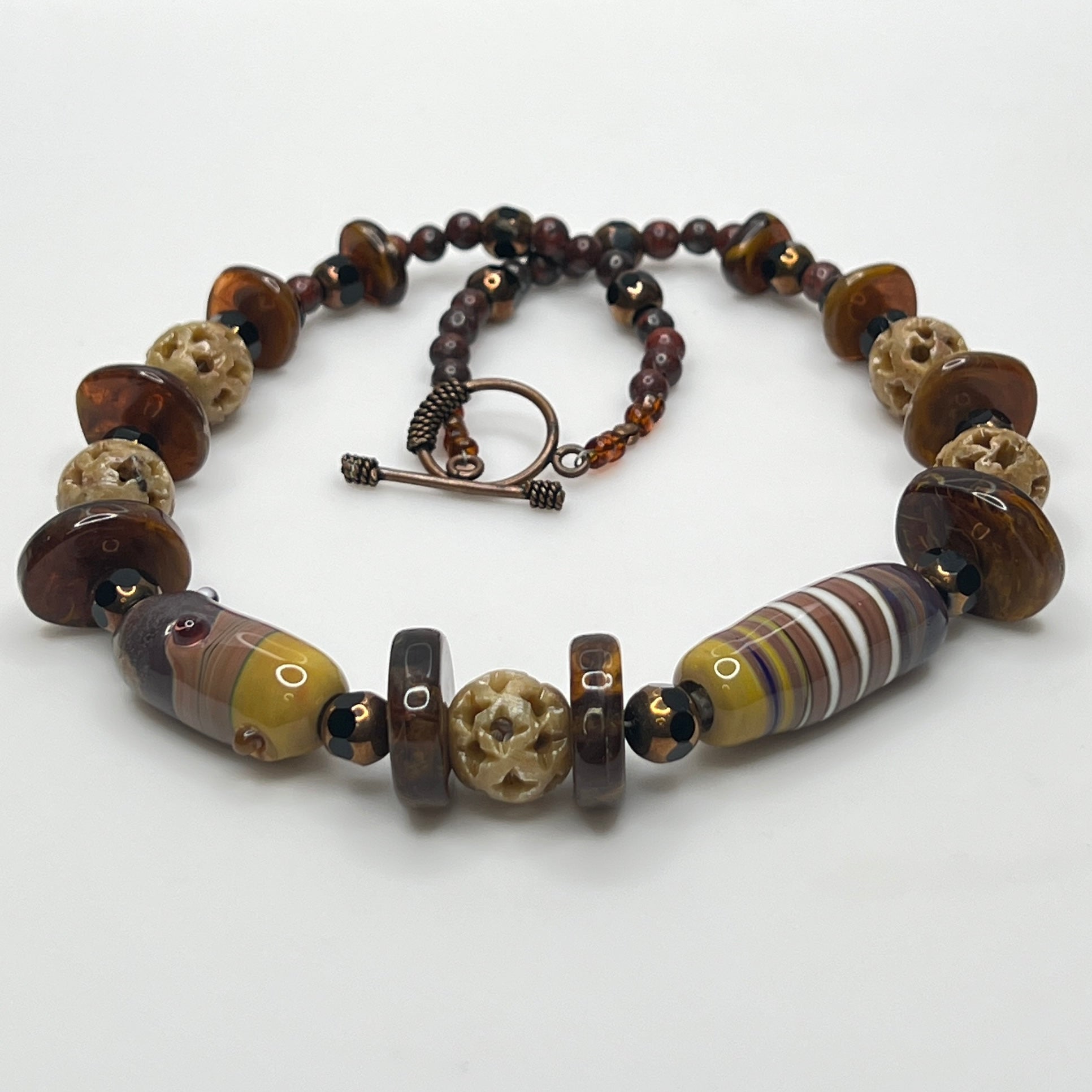 Vintage necklace with glass and carved stone beads in warm earthy tones