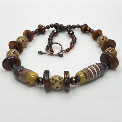 Vintage necklace with glass and carved stone beads in warm earthy tones
