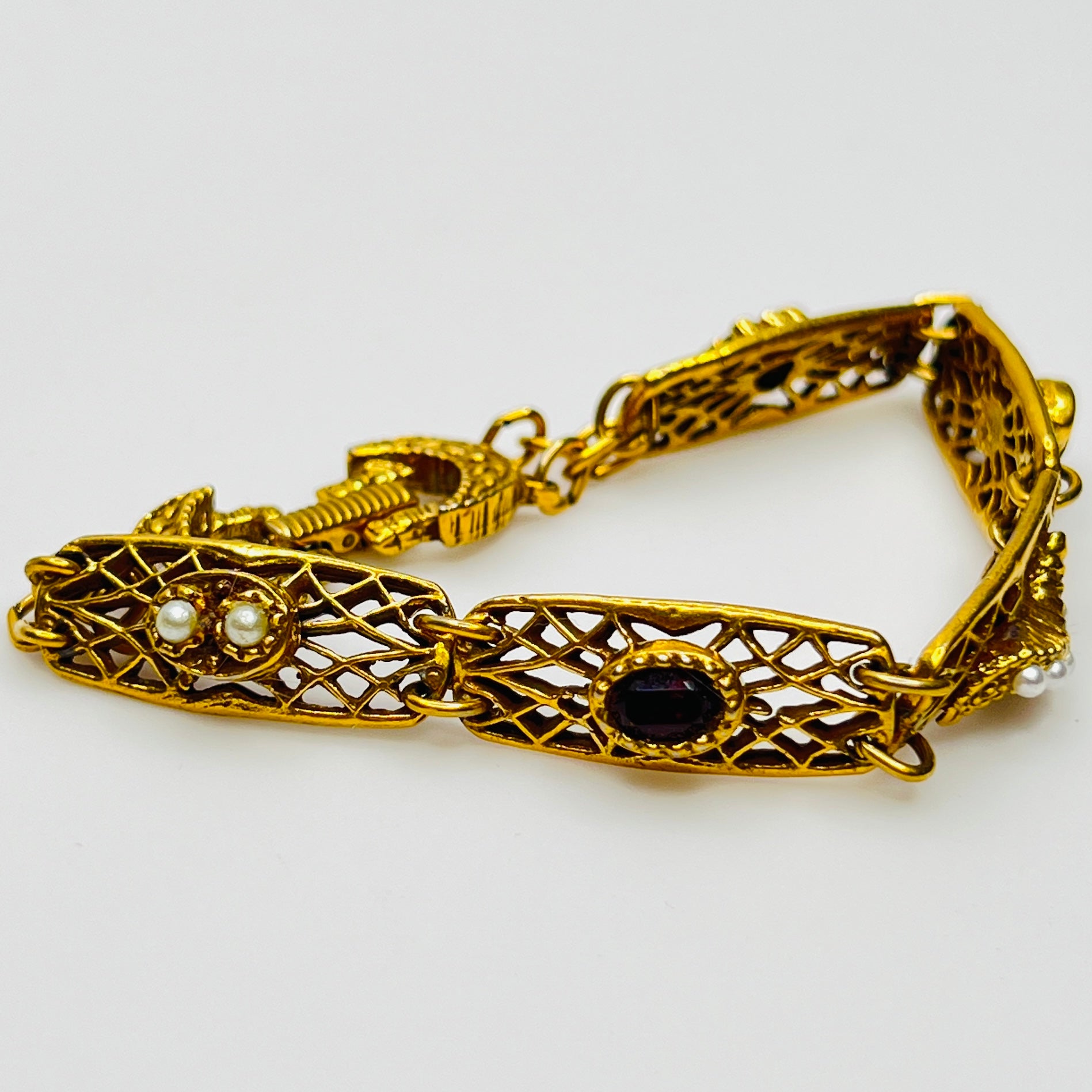 Filigree bracelet with varied gemstone details laid flat, fold-over clasp visible