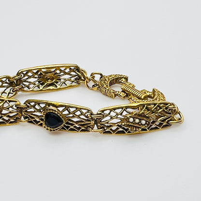 Filigree bracelet with varied gemstone details laid flat, fold-over clasp visible