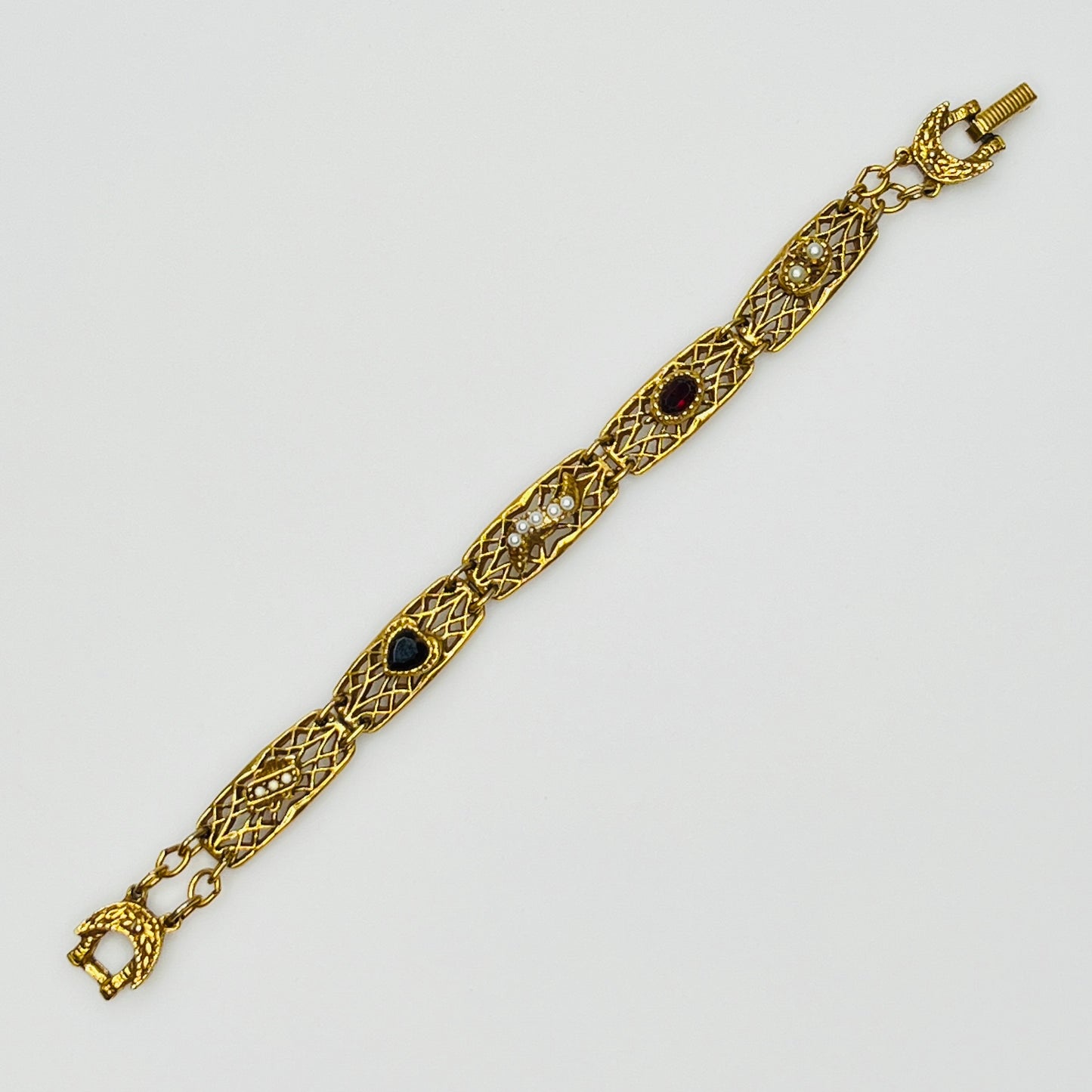 Filigree bracelet with varied gemstone details laid flat, fold-over clasp visible
