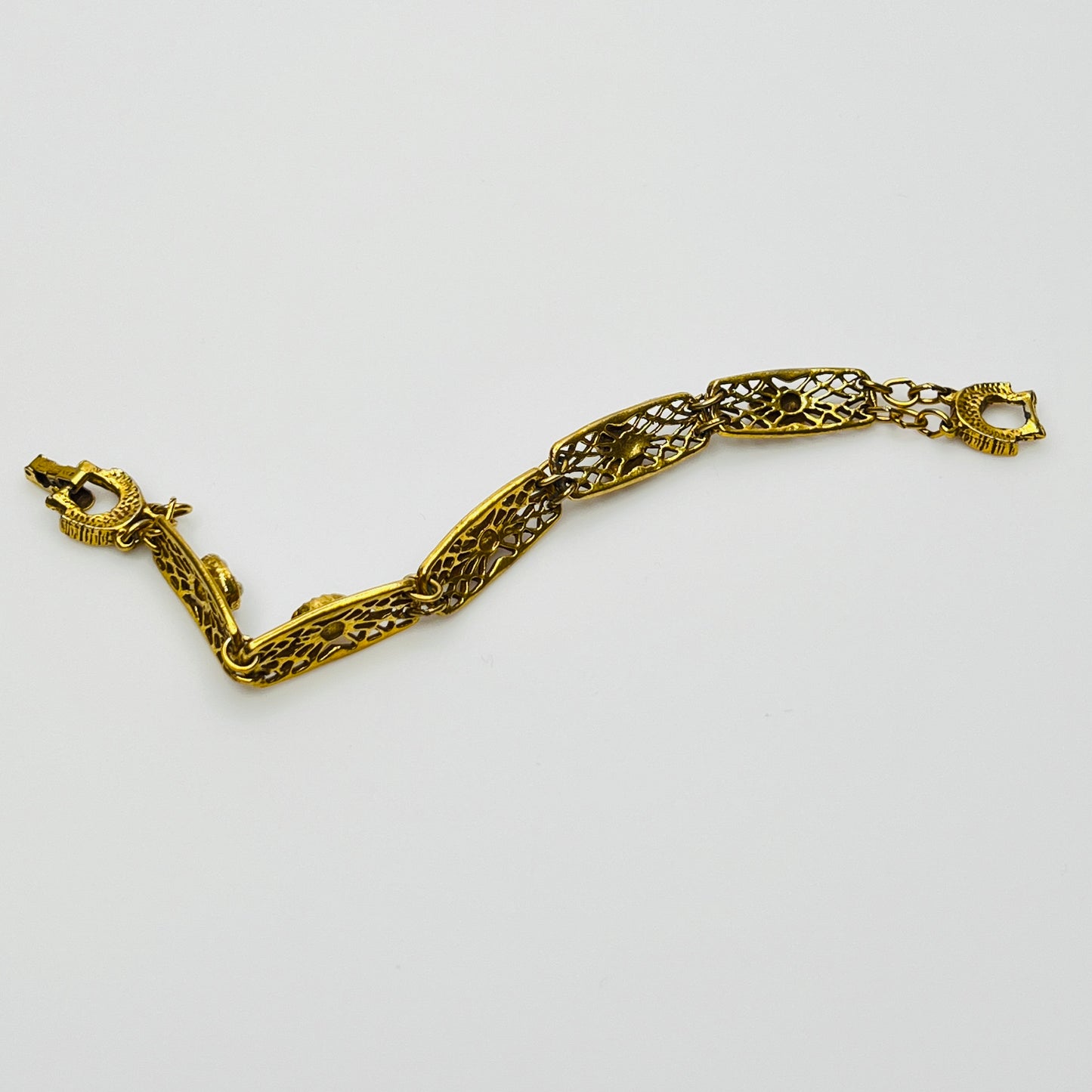 Filigree bracelet with varied gemstone details laid flat, fold-over clasp visible