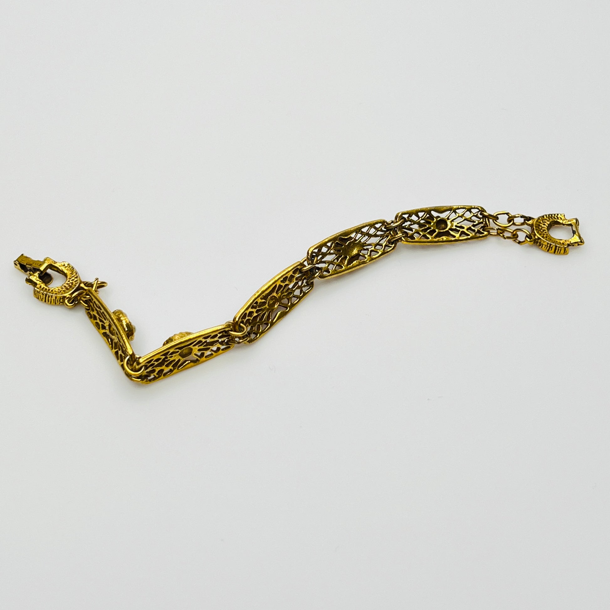 Filigree bracelet with varied gemstone details laid flat, fold-over clasp visible