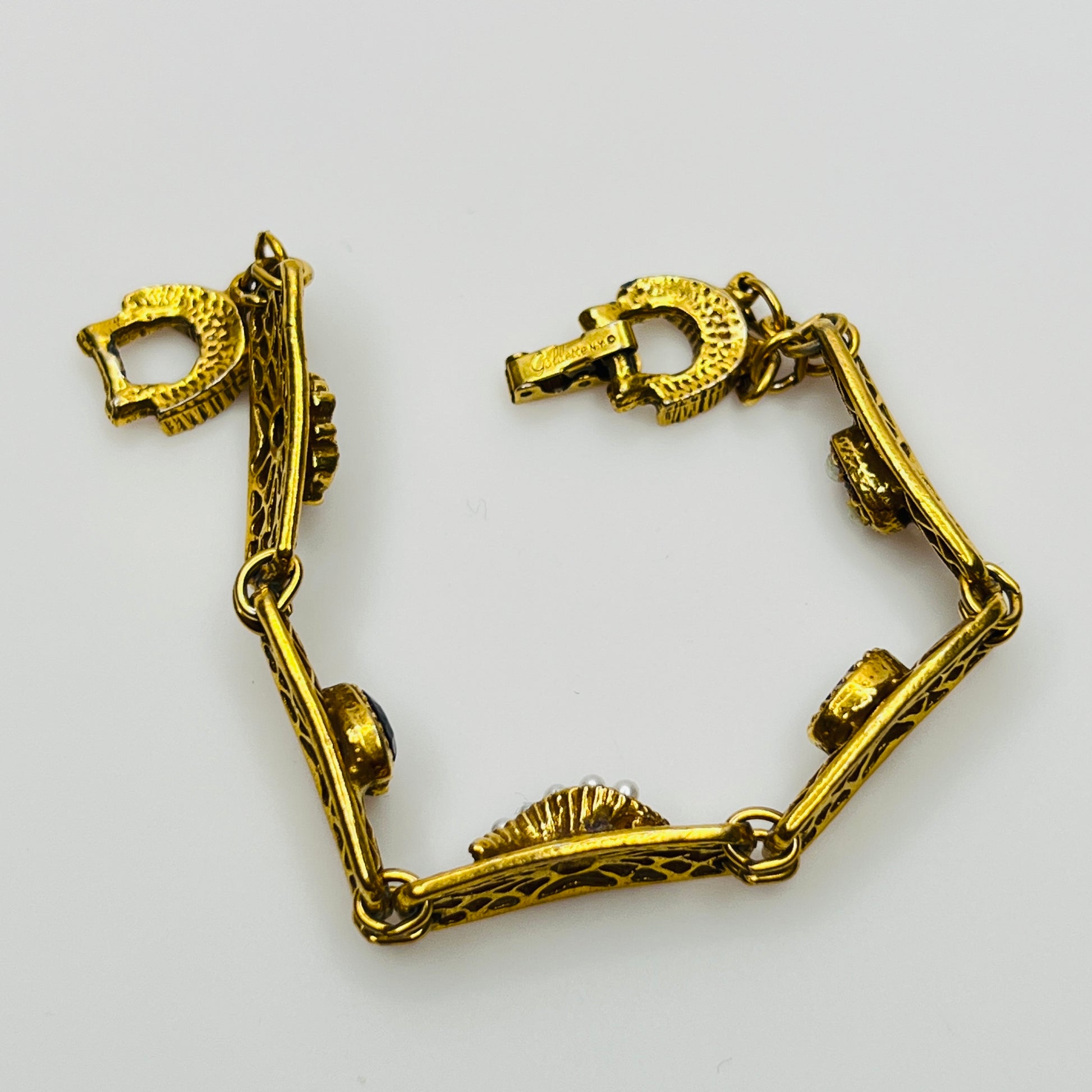 Filigree bracelet with varied gemstone details laid flat, fold-over clasp visible