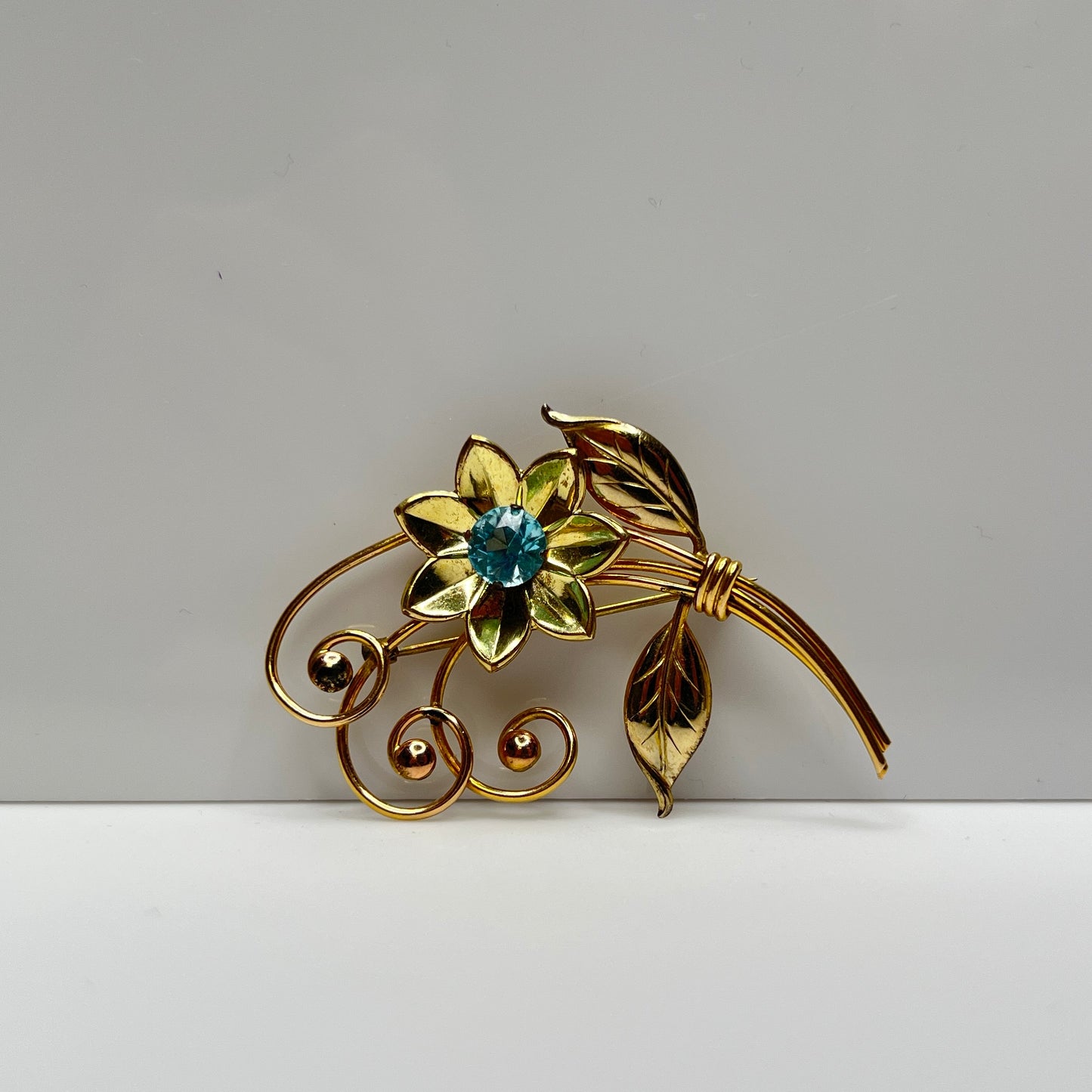 Vintage gold-filled floral brooch with blue rhinestone, signed Harry Iskin