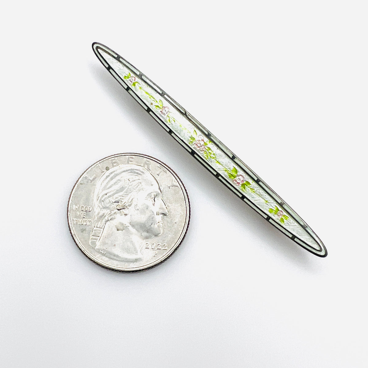 Edwardian floral enamel sterling bar brooch beside quarter for scale