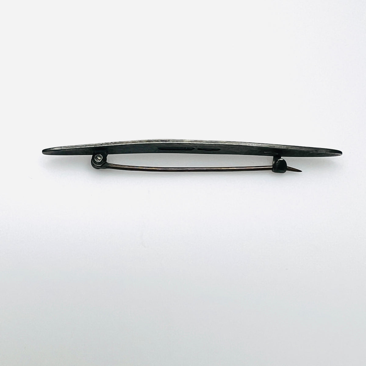 Side view of antique sterling silver enamel brooch showing C-clasp pin