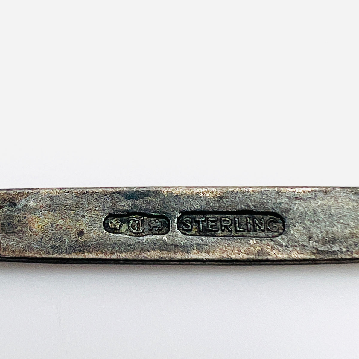 Antique brooch hallmark detail showing pictorial marks and STERLING stamp