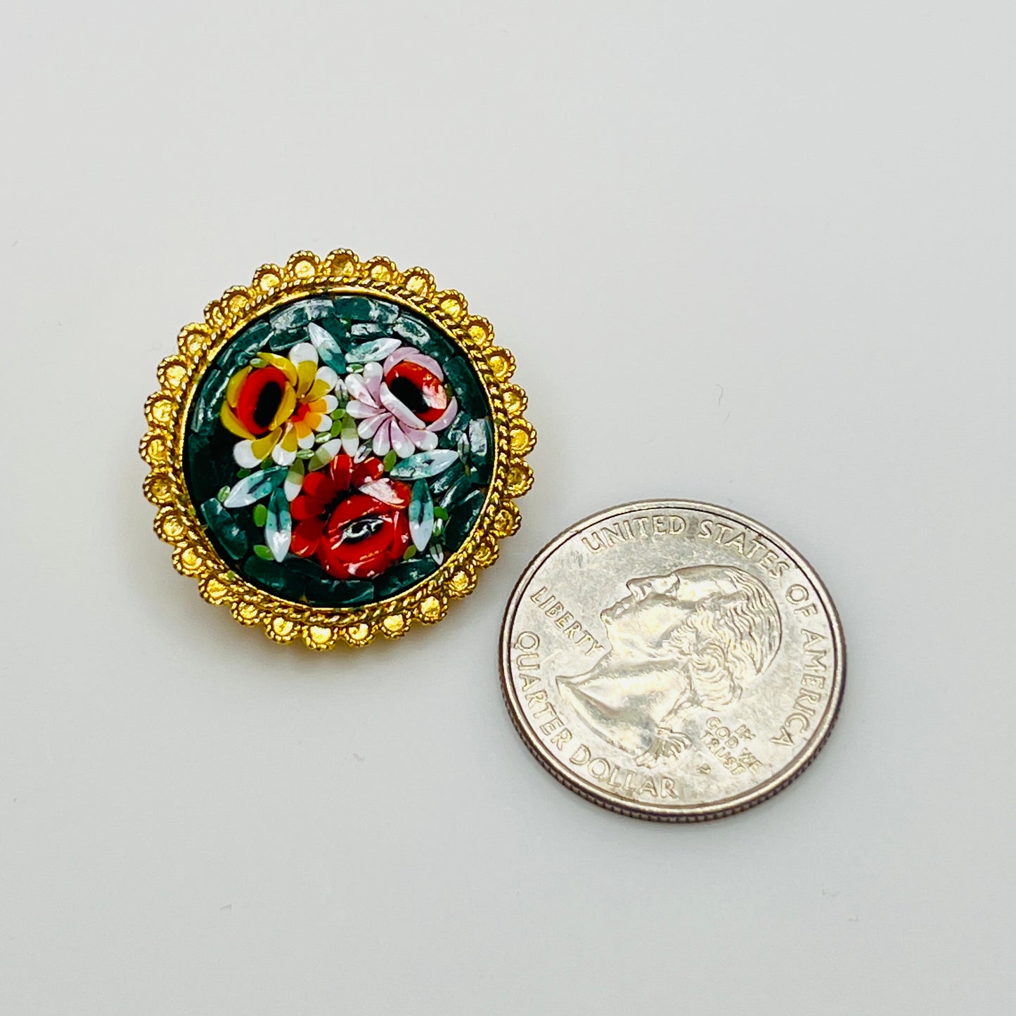 Close-up of round micro mosaic pin with red, pink, and yellow flowers