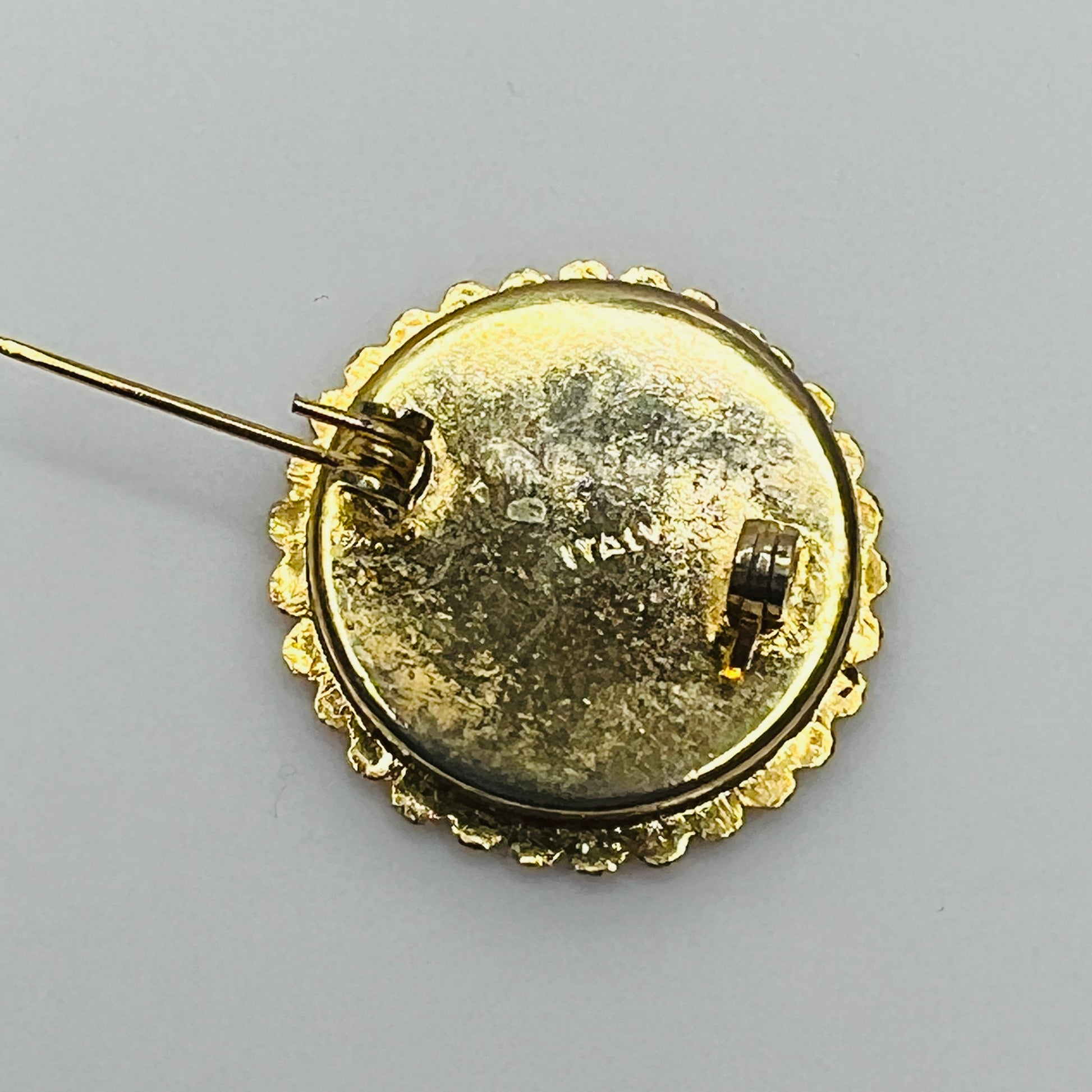 Close-up of round micro mosaic pin with red, pink, and yellow flowers