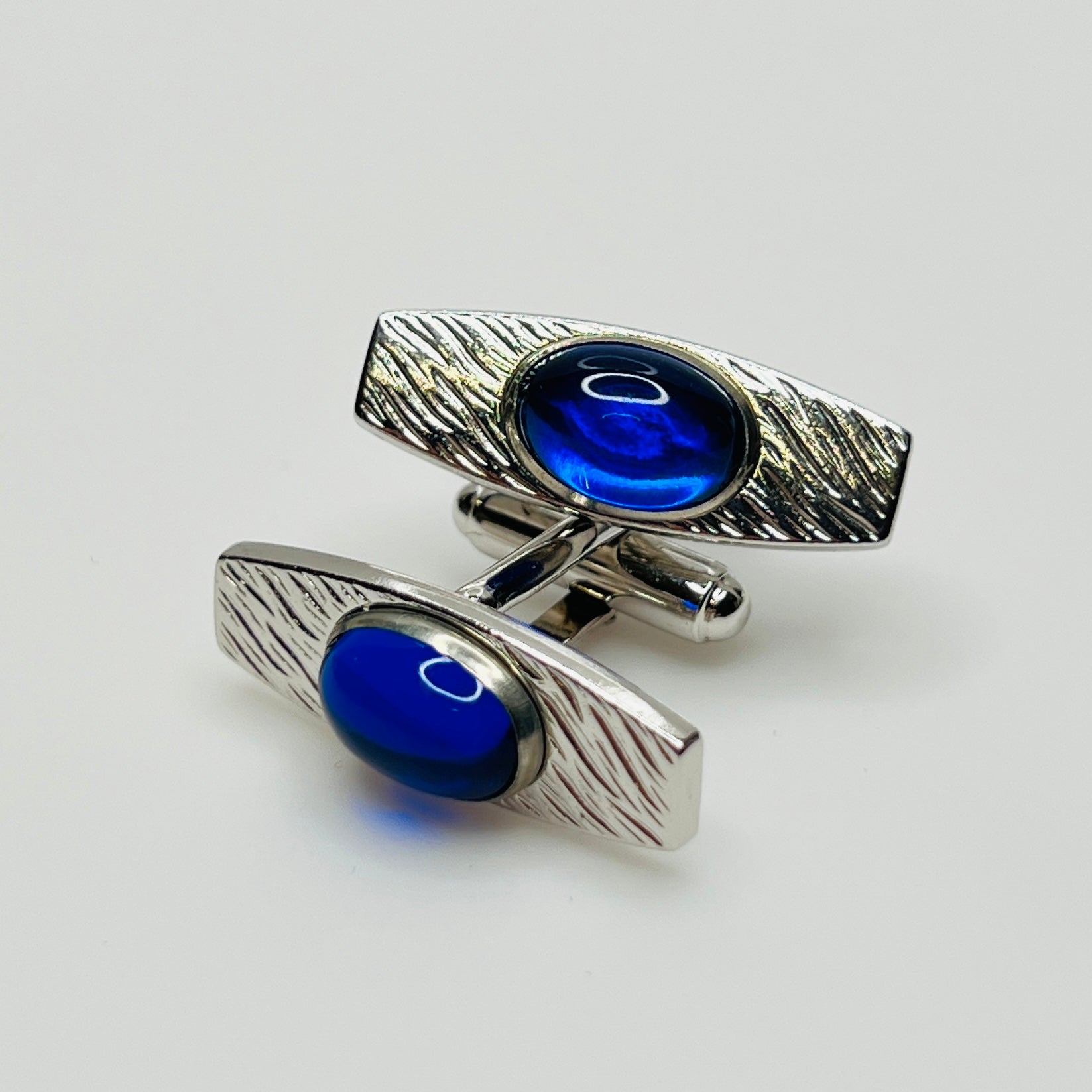 Silver-tone cufflinks with textured finish and vivid blue lucite cabochons, signed Anson