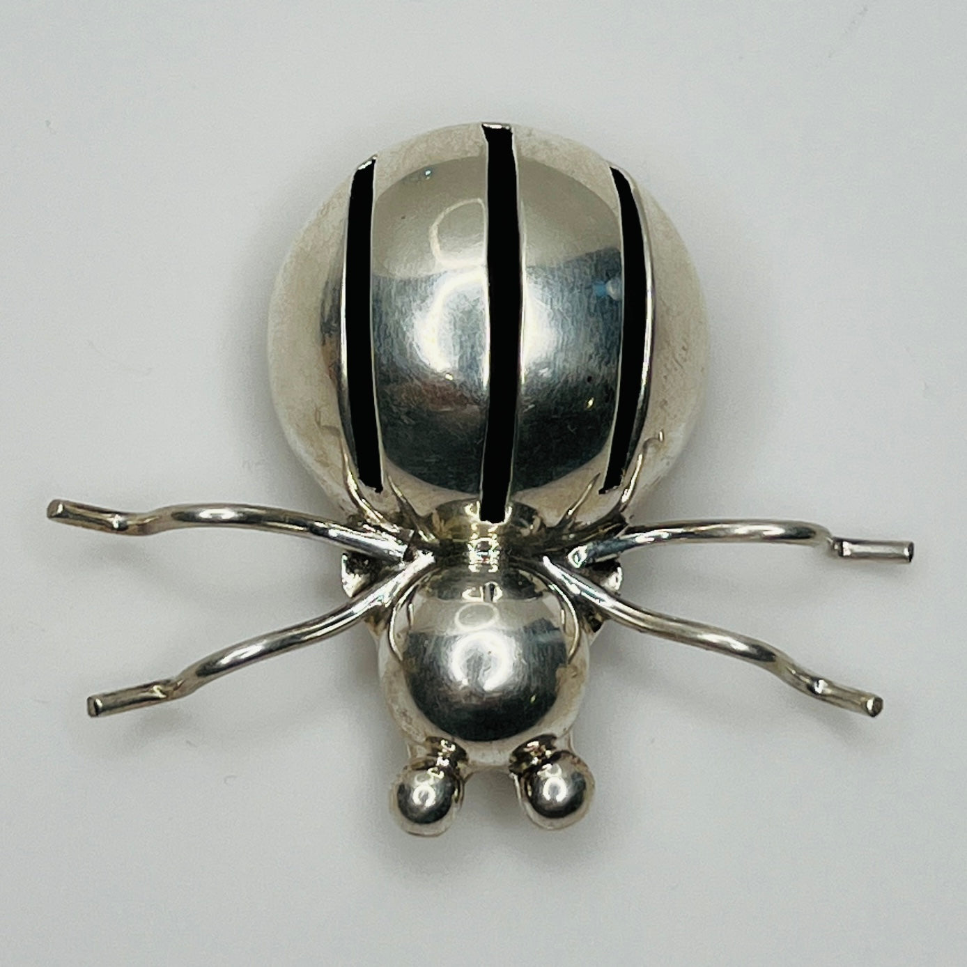 Sterling silver spider brooch with stylized body and curved legs