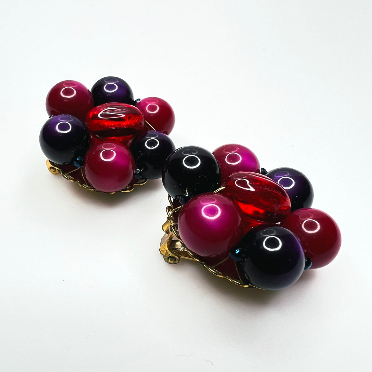 Side view of vintage Marvella dimensional bead cluster clip earrings with gold-tone metal settings.