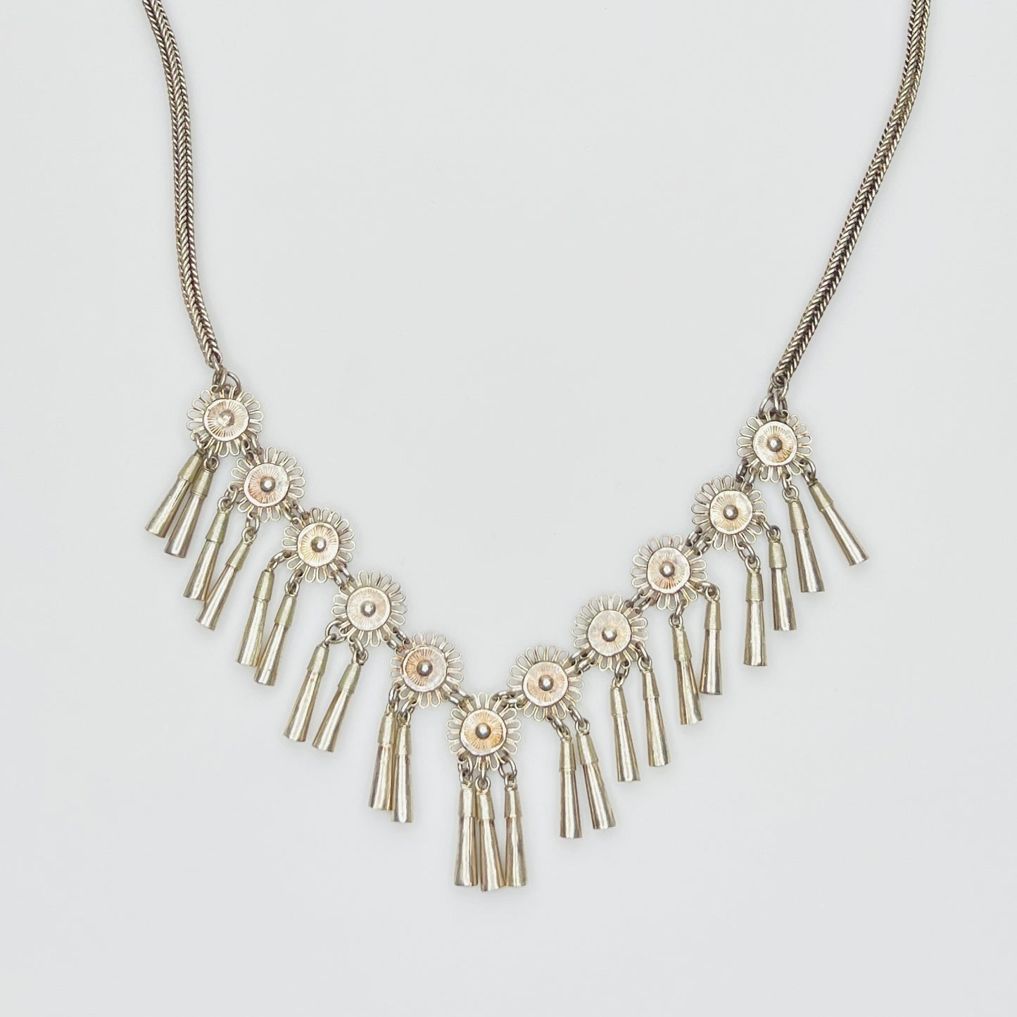 Close-up of silver floral medallions with cone tassels