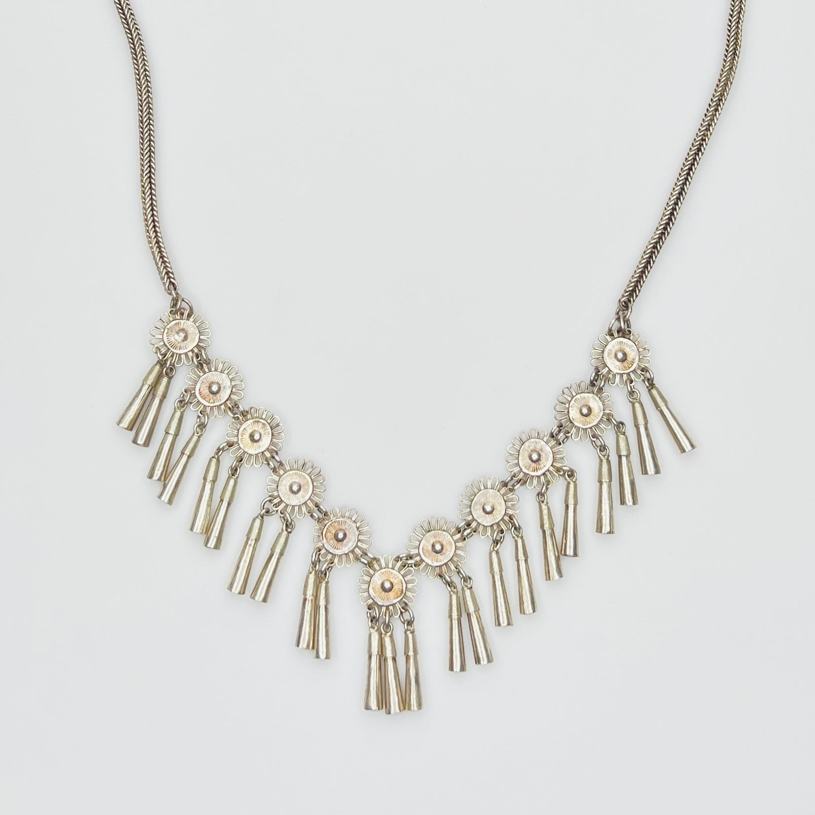 Close-up of silver floral medallions with cone tassels