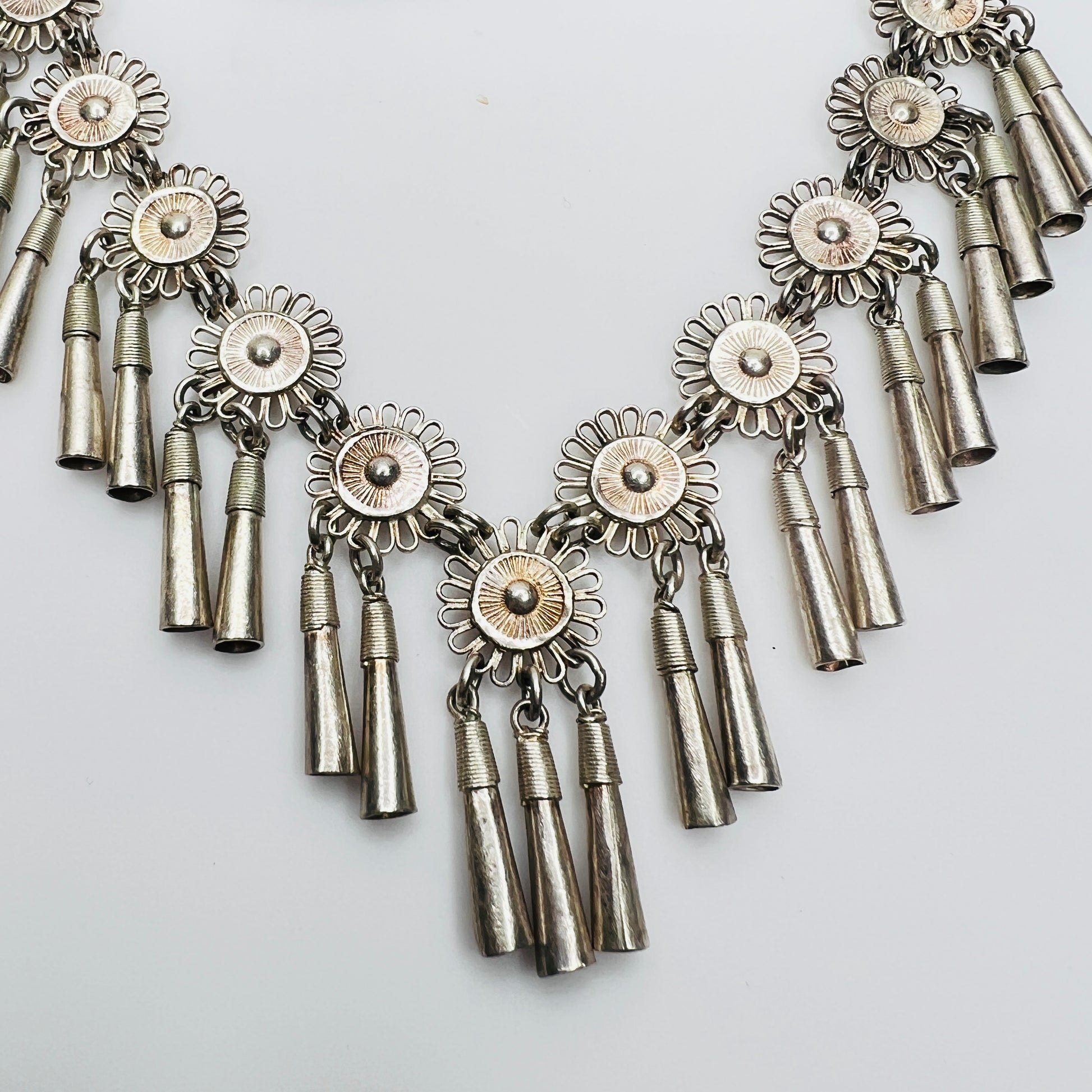 Close-up of silver floral medallions with cone tassels