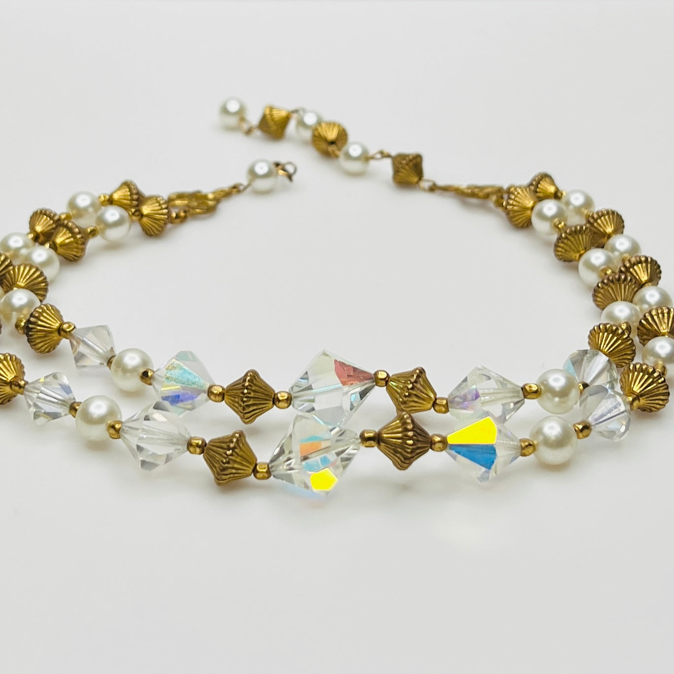 Double-strand necklace with faux pearls, iridescent crystals, and brass beads laid flat