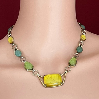 Monet necklace shown worn on model, featuring leafy cabochon shapes and central pendant