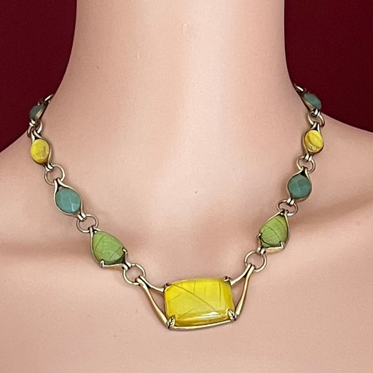 Monet necklace shown worn on model, featuring leafy cabochon shapes and central pendant