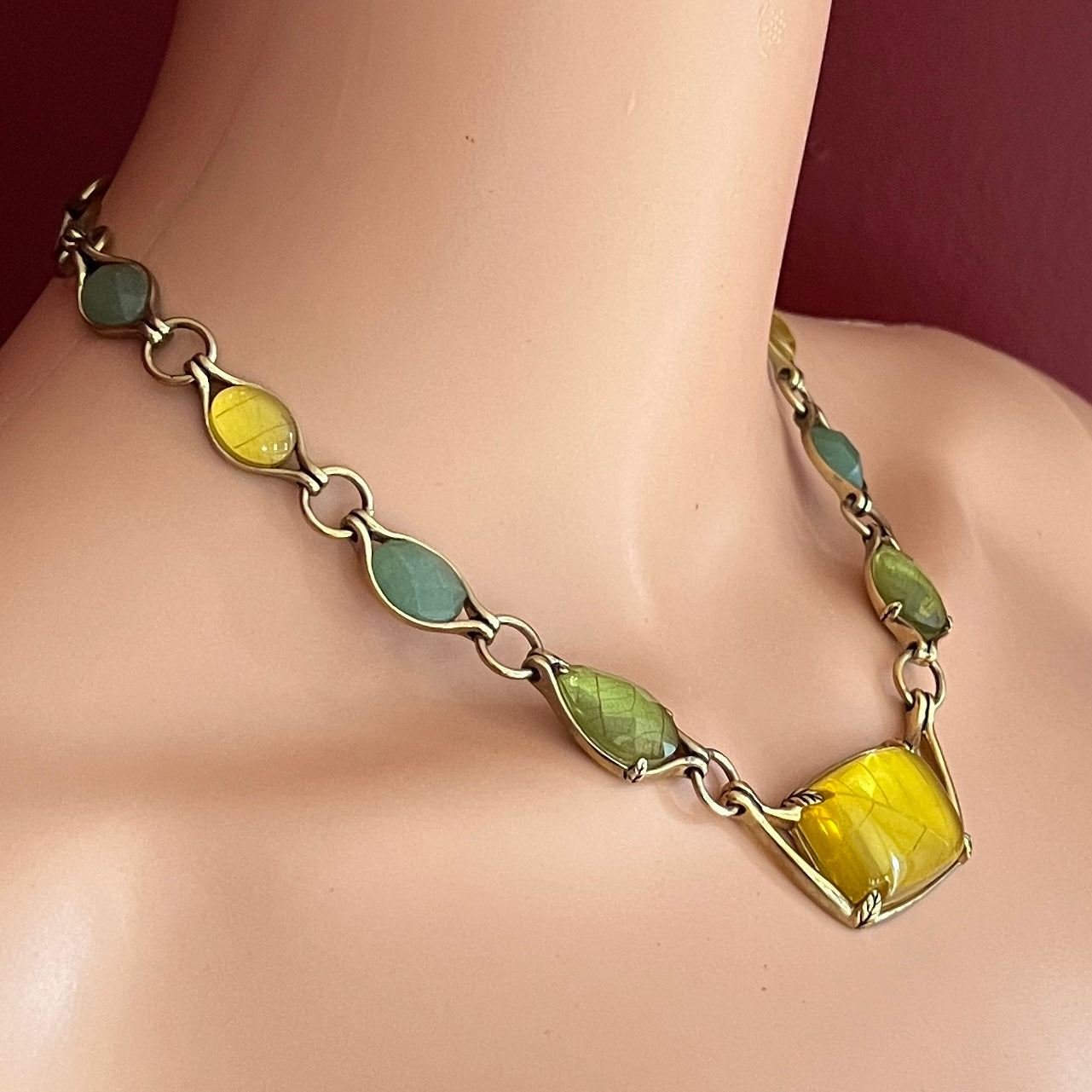 Monet necklace shown worn on model, featuring leafy cabochon shapes and central pendant