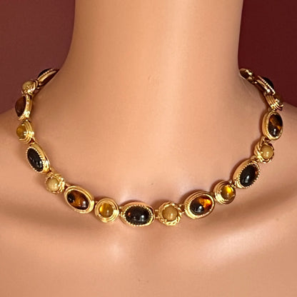 Model wearing goldtone Monet cabochon necklace with faux gemstone settings