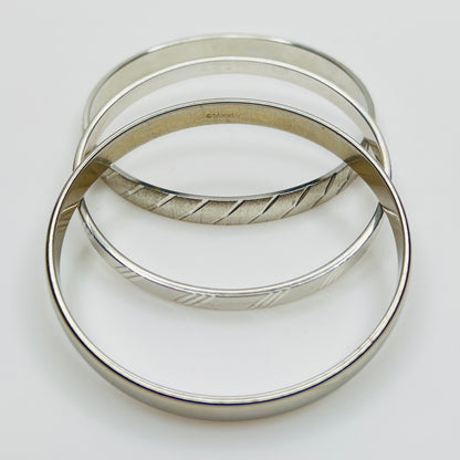Signed Monet silver tone bangle trio, smooth and textured
