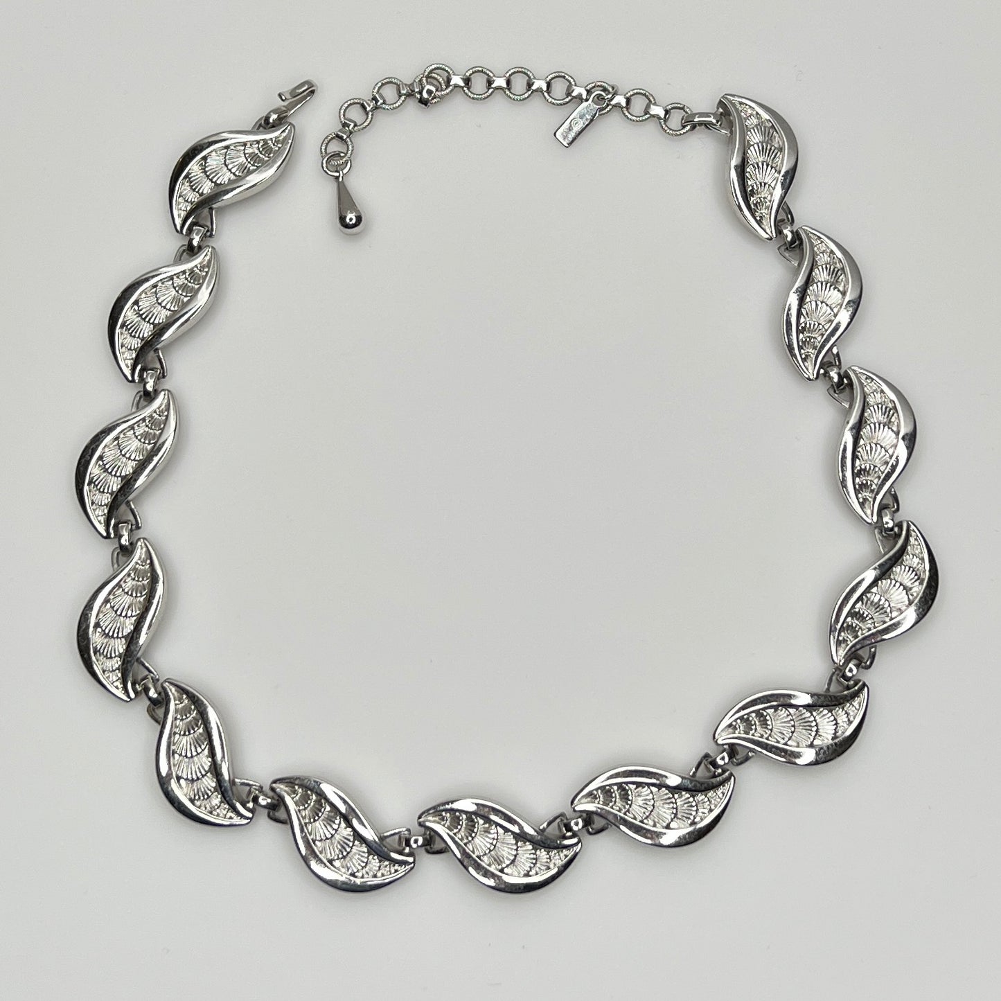 Overhead view of full silver Monet necklace with etched leaf design and extender chain