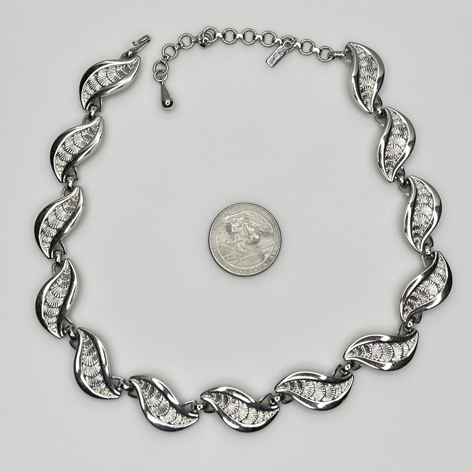 Overhead view of full silver Monet necklace with etched leaf design and extender chain