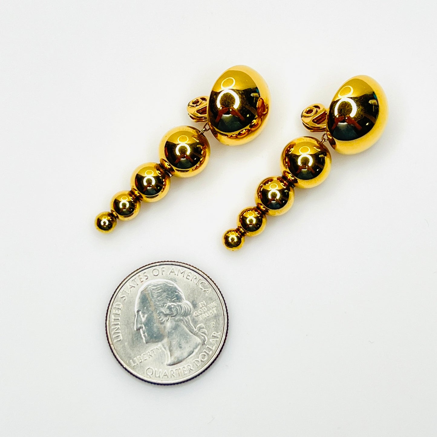 Monet gold graduated bead clip-on earrings shown with quarter for scale