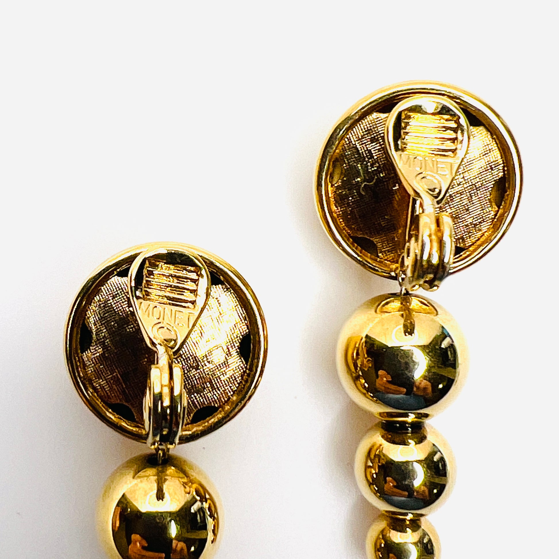 Back view of signed Monet graduated bead clip-on earrings with close up of Monet stamp