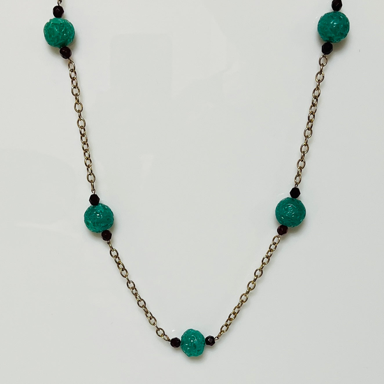 Long vintage necklace with green threaded glass beads and red spacers on gold-tone chain
