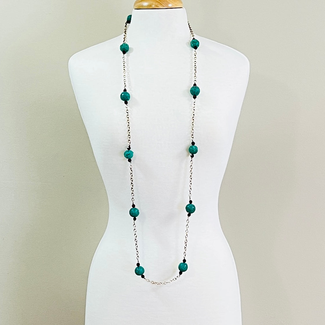 1950s glass bead necklace displayed on mannequin, emerald and ruby tones