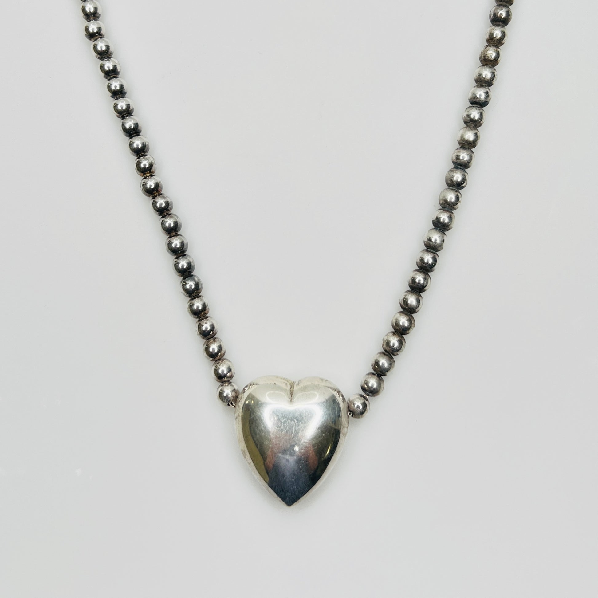 Close-up of silver puff heart pendant on white background