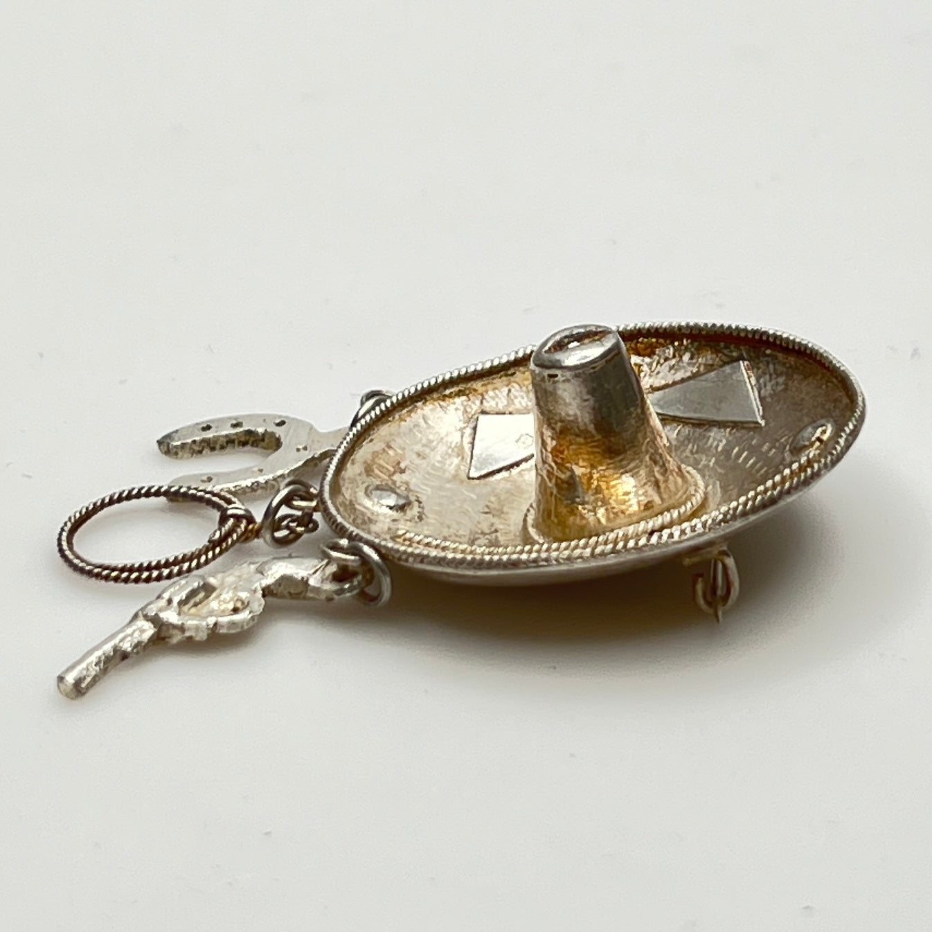 Vintage sombrero hat brooch in silver showing 3D brim and charm depth – angled view