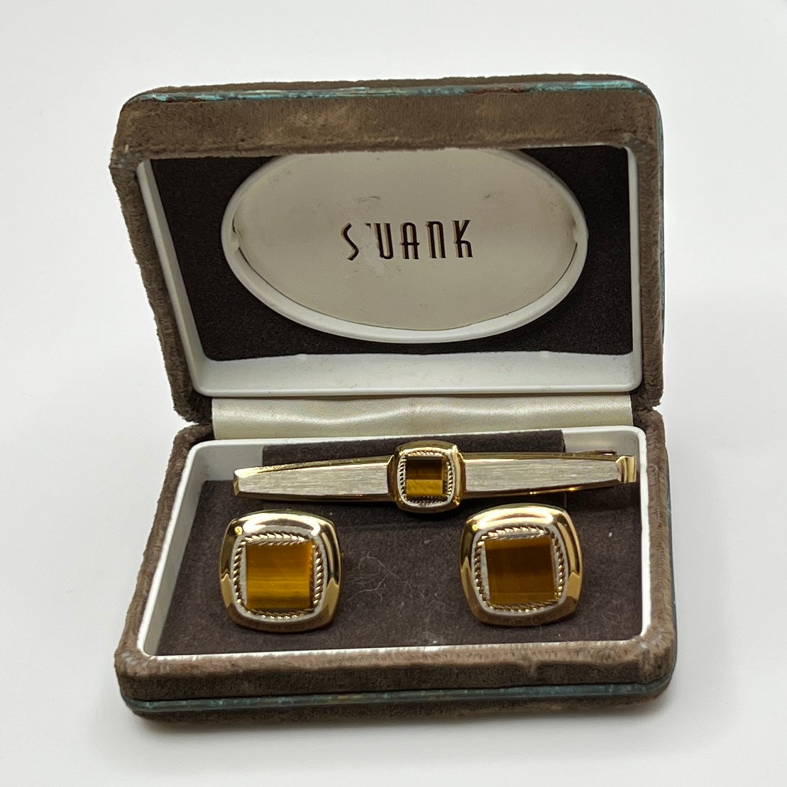 Gold cufflinks and tie clip set in a 'Suank' branded box on a white background