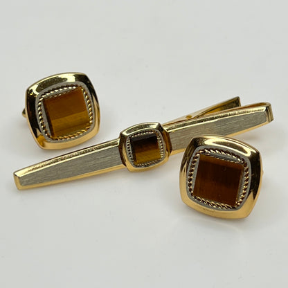 Gold tiger's eye cufflinks and tie clip set on a light gray background