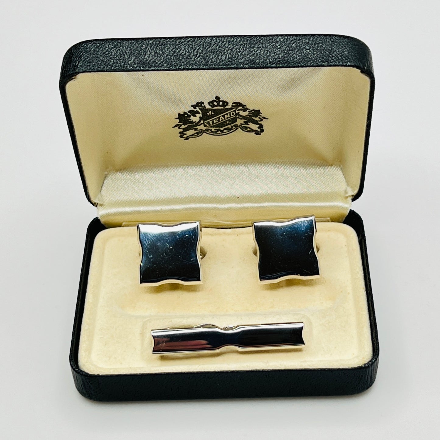 Cufflinks and tie clip set in a branded box on a light gray background