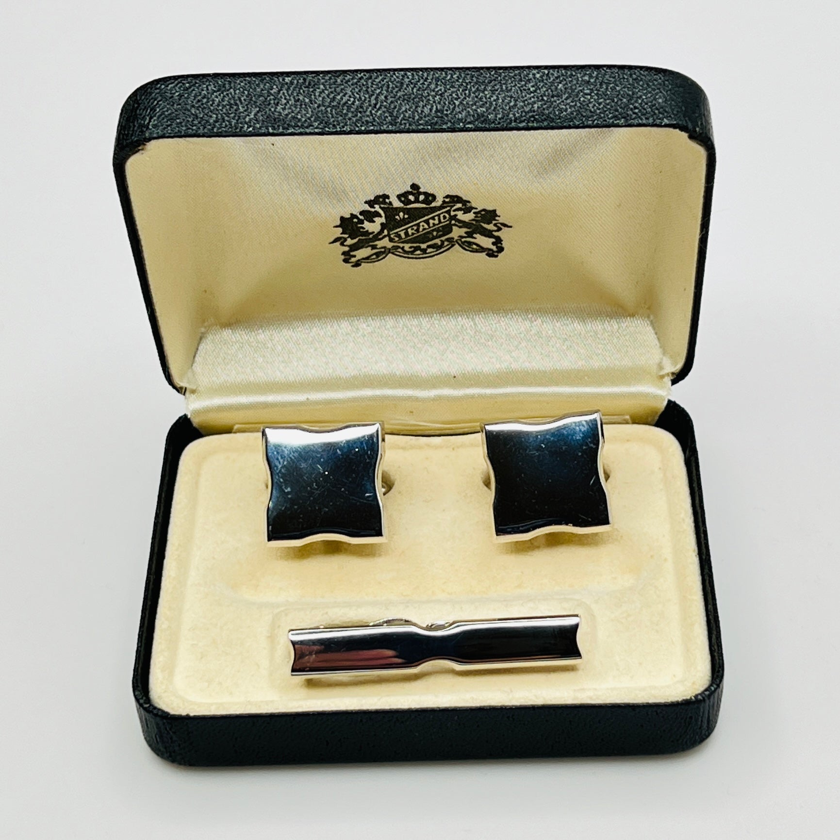 Cufflinks and tie clip set in a branded box on a light gray background