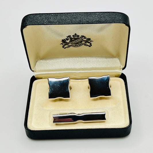 Cufflinks and tie clip set in a branded box on a light gray background