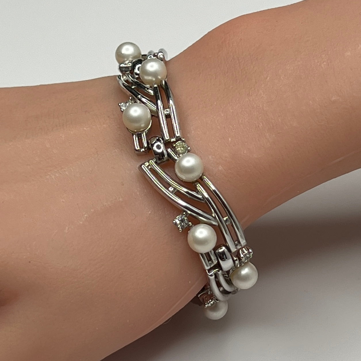 Trifari silver-tone bracelet with faux pearls and rhinestones worn on wrist